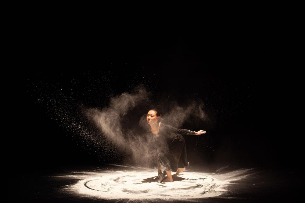 A dancer performs on stage, swirling in s和, creating a unique visual effect.